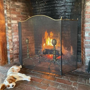 dog sleeping next to brick fireplace.