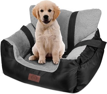 Puppy sitting in a plush dog car seat with a fuzzy gray interior and a washable black exterior.