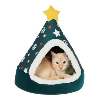 A blonde cat resting inside of a Frisco Holiday Dog & Cat Christmas Tree Cave Bed
