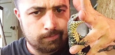 man poses for selfie with tiny crocodile
