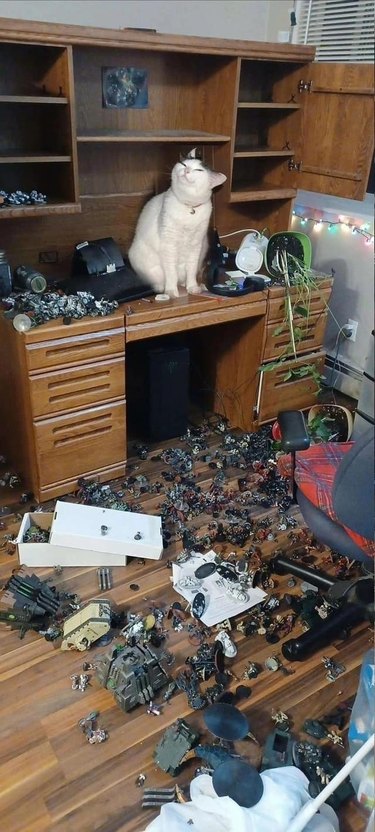 cat pushes giant pile of toy soliders off desk.