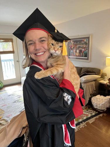 Woman and ginger cat graduate from college.