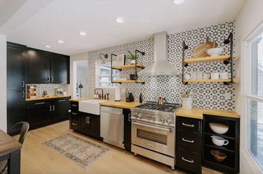 Modern Mountain Retreat kitchen with black and white geometric backsplash, open shelving, high-end appliances, and black cabinetry.
