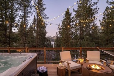 Large outdoor deck overlooking Big Bear Lake with a hot tub, fireplace with s'mores essentials, and lounge chairs.