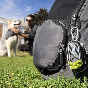 dog poop bag holder clipped onto backpack