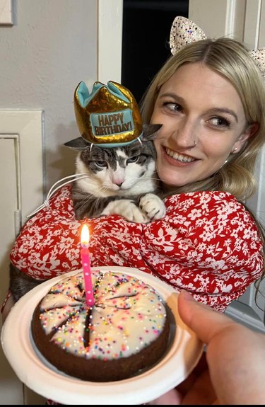 woman holding cat in happy birthday hat