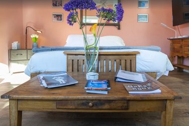 A queen bed, nightstand, and purple flowers at Nestled in the Trees in Santa Fe, NM