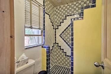 Intricately tiled shower in shades of yellow, blue, and off-white.