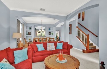 Living room with bright red sofas adjacent to dining area in Florida vacation home.