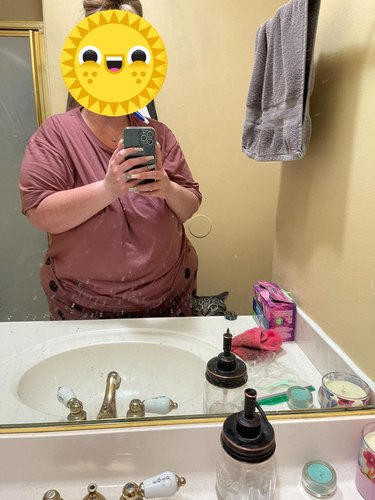 Cat accompanies woman to bathroom and peers over the vanity counter, looking at the mirror reflection.