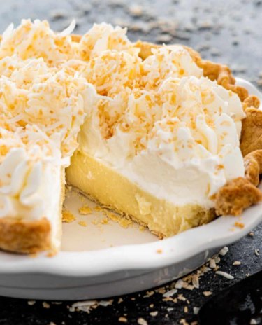 A coconut cream pie with a slice cut out of it.