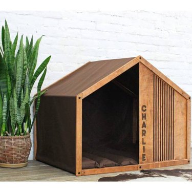 A plywood indoor dog house with a soft-sided tent wall, and soft cotton dog bed from Etsy
