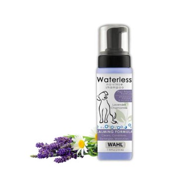 A bottle of Wahl Pet-Friendly Waterless No Rinse Shampoo for Animals against a white background. It has a pump design. A small bouquet of lavender and daisies is positioned next to it.