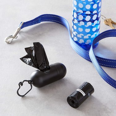 Amazon Basics Unscented Standard Dog Poop Bags pictured next to the clip-on dispenser