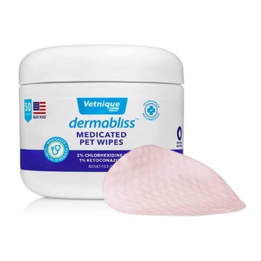 Vetnique Labs Dermabliss Anti-Itch and Medicated Wipes against a white background. Also in the photo is an example of what the wipes look like. They resemble round, textured cotton pads and have a light pink coloring.