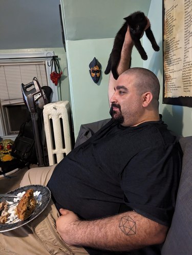 man holds cat up to keep food safe.