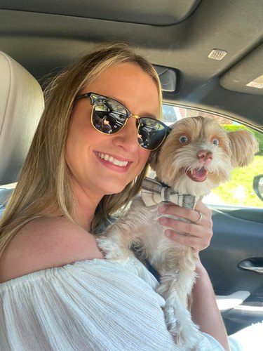 woman holds smiling dog in car