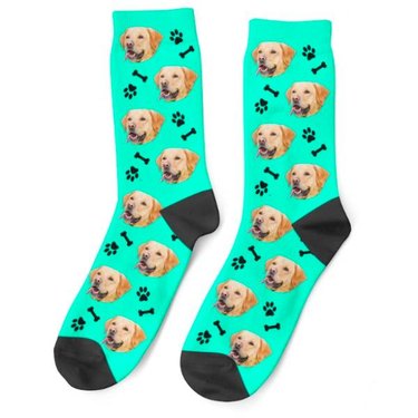 A pair of mint green and black socks with a dog's face printed all over them and paw prints and bones in the emtpty spaces