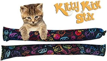 Kitten with two black and neon kicker toys and the words 'Kitty Kick Stix.'