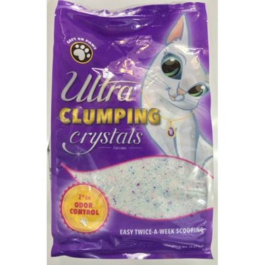 A 5-pound bag of Ultra Clumping Odor Control Low Dust Crystal Cat Litter against a white background. The bag is purple with a cartoon white cat on it. A badge on the bag says "1st in odor control."