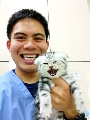 A veterinarian intern and a kitten smile for a photo.