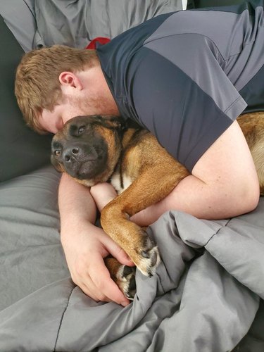 man snuggles with girlfriend's dog