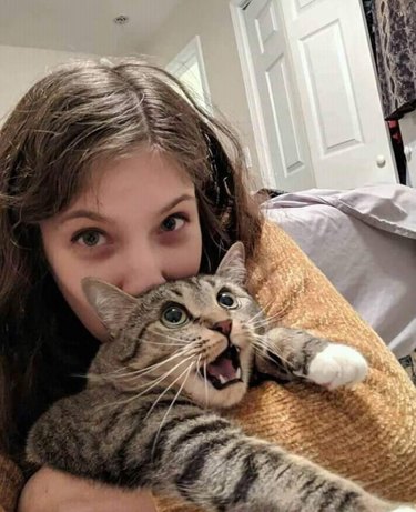 Cat attempting to escape woman's grasp