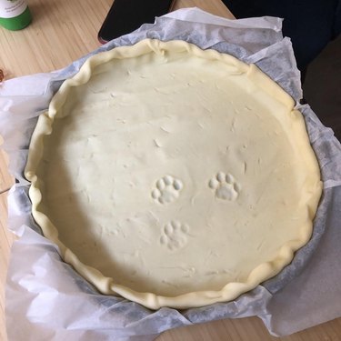 An uncooked pie crust with three cat paw prints in it.