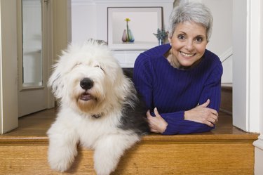 White haired woman in a dark blue shirt smiling next to a large white dog