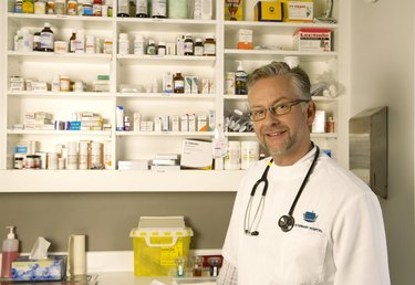 "Mature male vet standing in surgery, smiling, portrait"