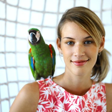 close up portrait of a woman sitting with a parrot on her shoulder