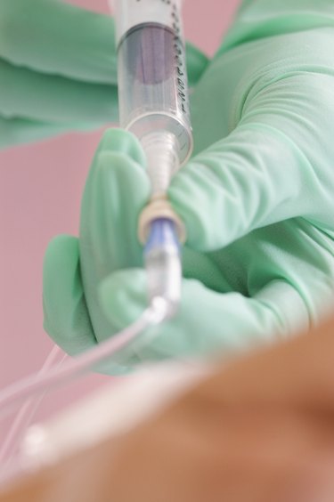 Nurse injecting fluid into tubing