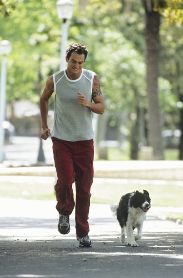 Mid adult man jogging with dog in park