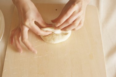 Woman making bagels, rolling dough, close up