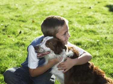 Boy (7-9) hugging dog, smiling