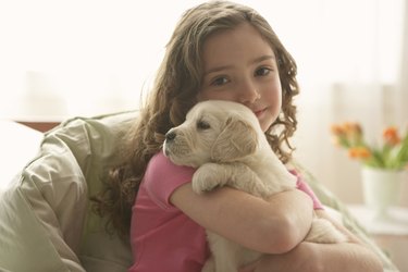 Young girl (8-10) holding dog, portrait