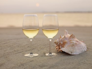 Champagne glasses and shell on beach