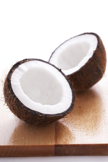 Split coconut on wooden board, close-up