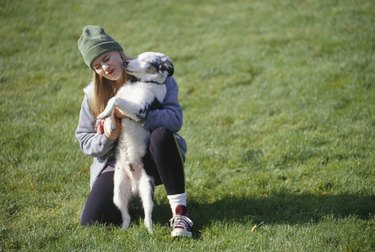 Girl (8-9) crouching in park hugging dog