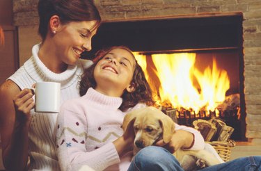 Mother and daughter with puppy by fireplace