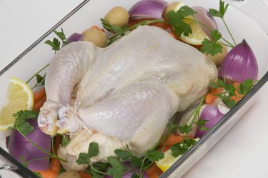 Uncooked chicken on a bed of vegetables
