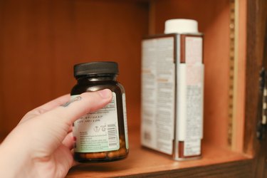 Hand reaching into cabinet and grabbing a medicine bottle