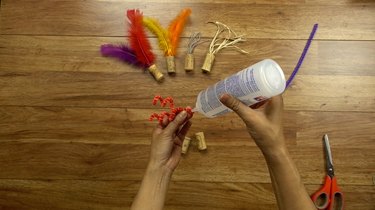 Gluing pipe cleaner for DIY cat toys out of wine corks.