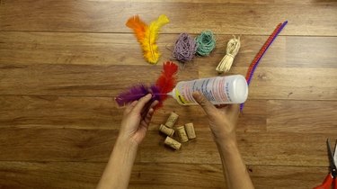 Gluing feather for DIY cat toys out of wine corks.