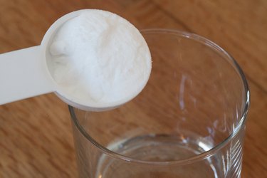 A spoon of white powder being poured into a beaker
