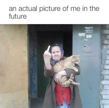 Picture of an elderly woman holding a cat, flipping off the camera