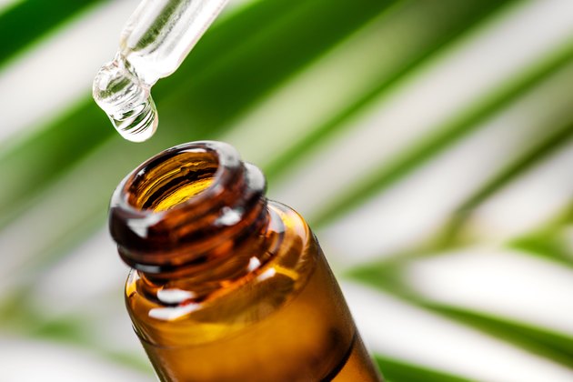 essential oil bottle and dropper with plant leaf in background