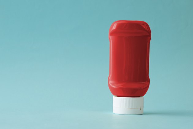 Bottle of ketchup against a blue background.