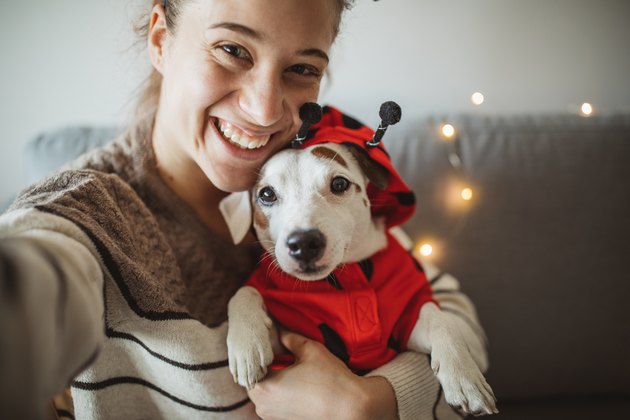 woman posing with small dog in ladybug costume