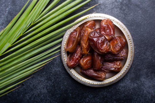 Dish of dates next to palm leaf